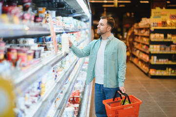 Customer choosing milk in dairy products section of supermarket