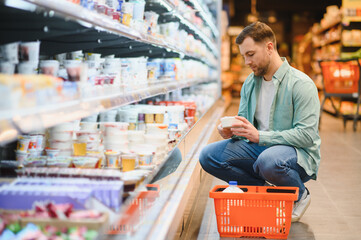 Customer choosing yogurt in dairy products section of supermarket