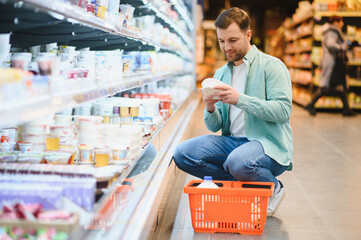 Customer choosing yogurt in supermarket dairy section