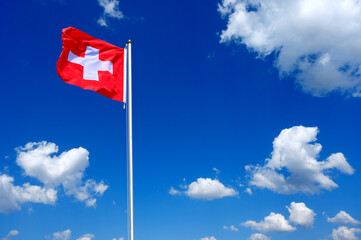 flag of Switzerland fluttering in the blue sky with cumulus clouds