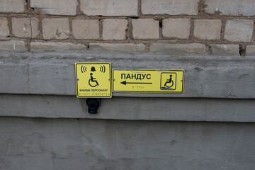Tactile accessibility signs and call button for people with disabilities on a wall