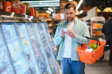 Customer reading product label in supermarket refrigerator section