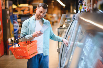 Customer choosing frozen food, reading product information in supermarket