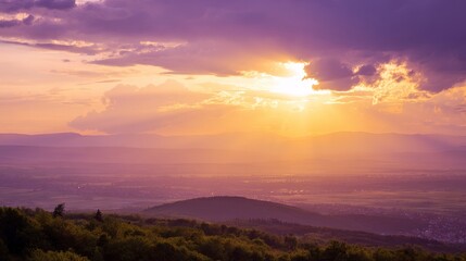 Obraz premium Golden sunset over a serene landscape, warm light through clouds, orange and purple hues blending in harmony