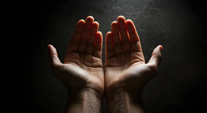 Open hands reaching up in prayer or supplication, dark background.