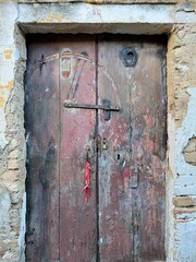 Old weathered door with peeling paint in a traditional Greek village. The textured surface reveals the charm and history of rustic Mediterranean architecture and rural life.
