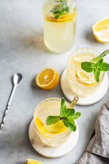 Two glasses of fresh drink lemonade with lemon, mint and ice on a light background with bottle