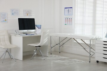Doctor's workplace with modern computer and examination table in medical office