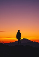 Silhouette of a Person on Mountaintop at Sunset - A lone figure stands atop a mountain, silhouetted against a vibrant sunset. The symbolizes peace, solitude, achievement, contemplation
