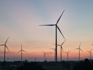 Wind Turbines in Sunset: Majestic wind turbines silhouetted against a vibrant sunset, representing a commitment to renewable energy.
