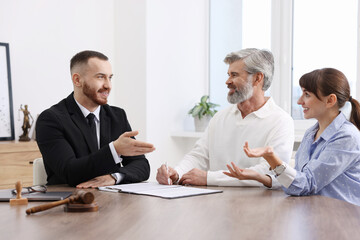 Couple having meeting with professional notary at wooden desk indoors
