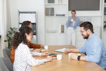 Obraz premium Colleagues eating and chatting during lunch break in office