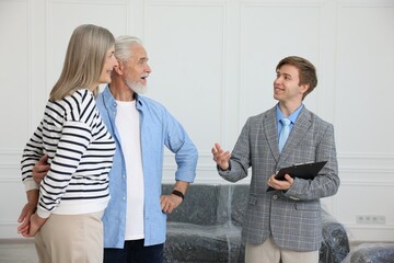 Smiling real estate agent with clipboard working with couple at home