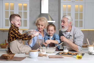 Grandparents and their grandkids cooking together at white marble table in kitchen