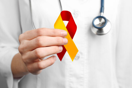 World Hepatitis Day. Doctor with yellow-red awareness ribbon, closeup
