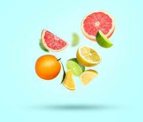 Different fresh citrus fruits falling on light blue background