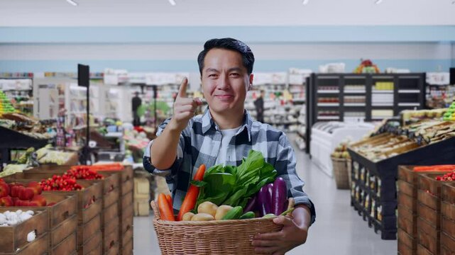 Asian Male Farmer With Vegetable Basket Smiling And Making Honest Gesture in Grocery Store