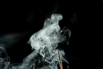 Dancing incense smoke with light in the dark.