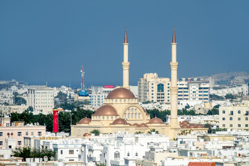 Naklejka premium Oriental architecture. A white Arab city in the foothills against background of dry desert mountains. White sunscreen color. Grand Mosque. Oman