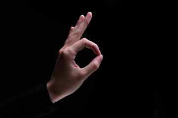 Female hand showing the ok gesture on a black background. Okey hand sign
