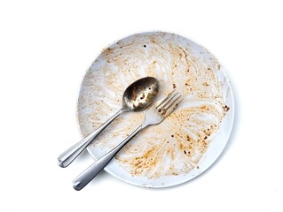 Dirty white plate with leftovers food with spoon and fork on top isolated on white background