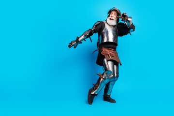 Obraz premium Playful aged knight posing in historical armor with a bright blue background