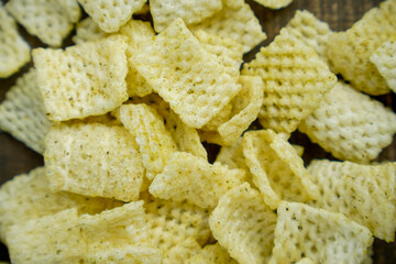 full screen view of hollow net chips with a sprinkling of fine spices on a wooden table. hollow net chips on wooden table surface.