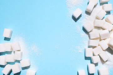 White sugar cubes on blue background top view flat lay. Scattered sugar cubes. Abstract pattern of...