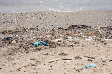 Polluted sea coast, plastic waste lying on the sand, environmental problems