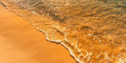 Sand on the beach and sea waves in the morning, orange tone.