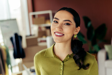 Confident young woman smiling in an atelier workspace showcasing modern fashion and professional career essence