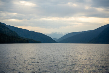 Early morning landscape of Teletskoye lake in Altai Russia. Calm water, soft light and serene mountain atmosphere near Artybash