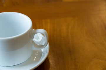 White ceramic coffee cup on wooden table, empty mug with saucer