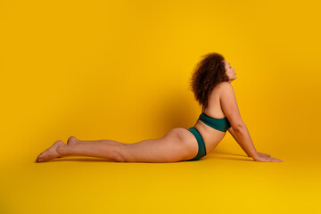 Confident young woman embracing self love and individuality while practicing yoga on a vibrant...