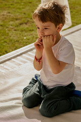 Little cute boy in the sunglasses enjoying summer on the sun bed in hotel of Turkey and biting his nails.