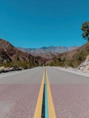 Asphalt Road Cutting Through Desert Landscape Under Clear Blue Sky