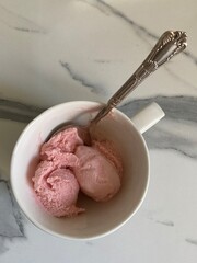 Ice cream with strawberry scent in cup on kitchen table top view