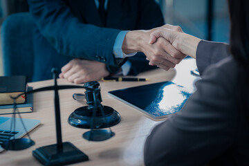 Handshake in office with legal documents and hammer on table. Judge and client shake hands in courtroom background after good cooperation in meeting or giving legal advice.