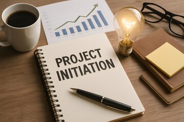 A spiral notebook titled project initiation rests beside a lit bulb, pen, and growth chart. Concept of strategic planning kickoff and fresh idea generation.