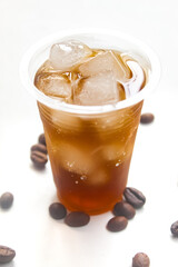 iced coffee in a plastic cup with coffee beans isolated on a white background