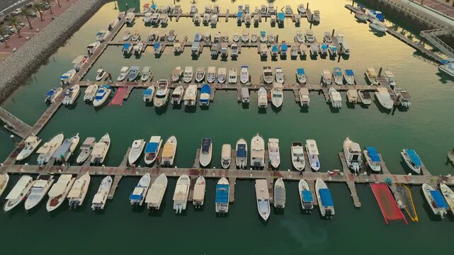 4K aerial drone view of a luxury marina in Kuwait with rows of boats docked during sunset. Ideal for travel, tourism, lifestyle, or real estate footage.
