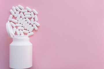 White tabletts or pills on the pink background with place for text.