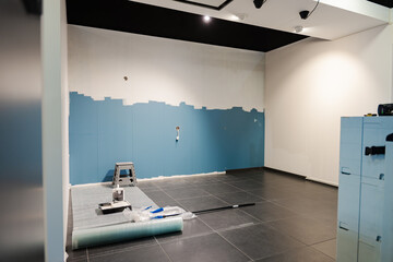 Mur bleu en cours de peinture blanche, capturant le contraste des couleurs et l'instant du...
