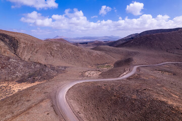 Dirt road winding through red volcanic hills in Fuerteventura