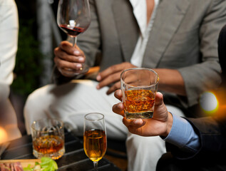 Businessman with friends and whiskey for a party in a bar or restaurant.