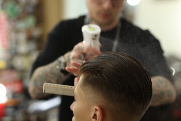 Professional barber making stylish haircut in barbershop, closeup