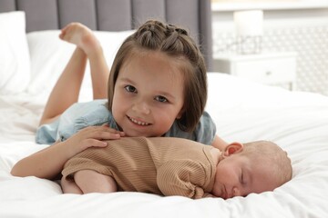 Cute girl and her little sister on bed at home