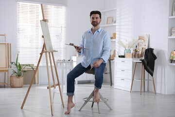 Man painting picture on easel in artist's studio