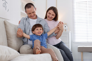 Obraz premium Cute little boy and his parents on sofa at home. Lovely family