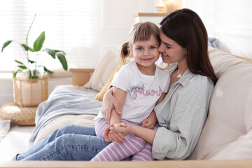 Happy mother and her cute daughter on sofa at home